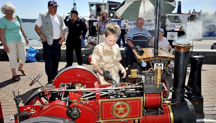 A child fascinated by a small steam engine at Poole Quay